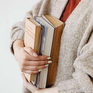 kaboompics_A young woman in a woolly sweater holds books
